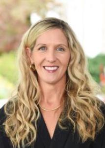 Daniel Downs with long blonde hair, black blouse, smiling.