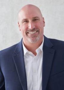 Headshot of Gregory Fosco with a blue suit jacket, white shirt, and gray facial hair.