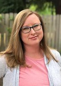 Jennifer Nyland headshot with long light brown hair, glasses, pink shirt and gray cardigan.