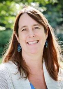 Headshot of Krista Wilkinson with long brown hair, blue and green top, and white sweater.
